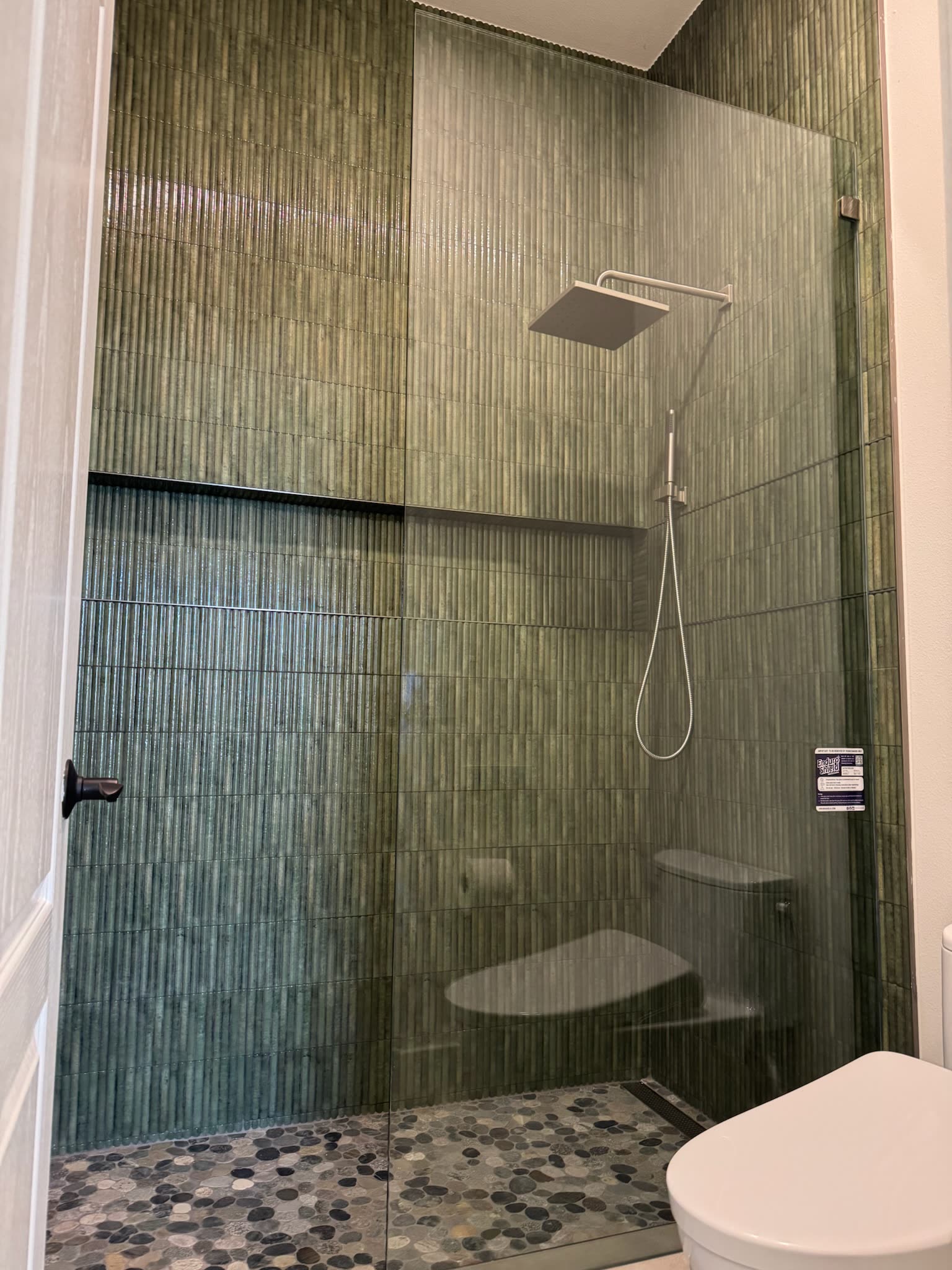 Walk-in shower with glass mosaic tile and pebble floor