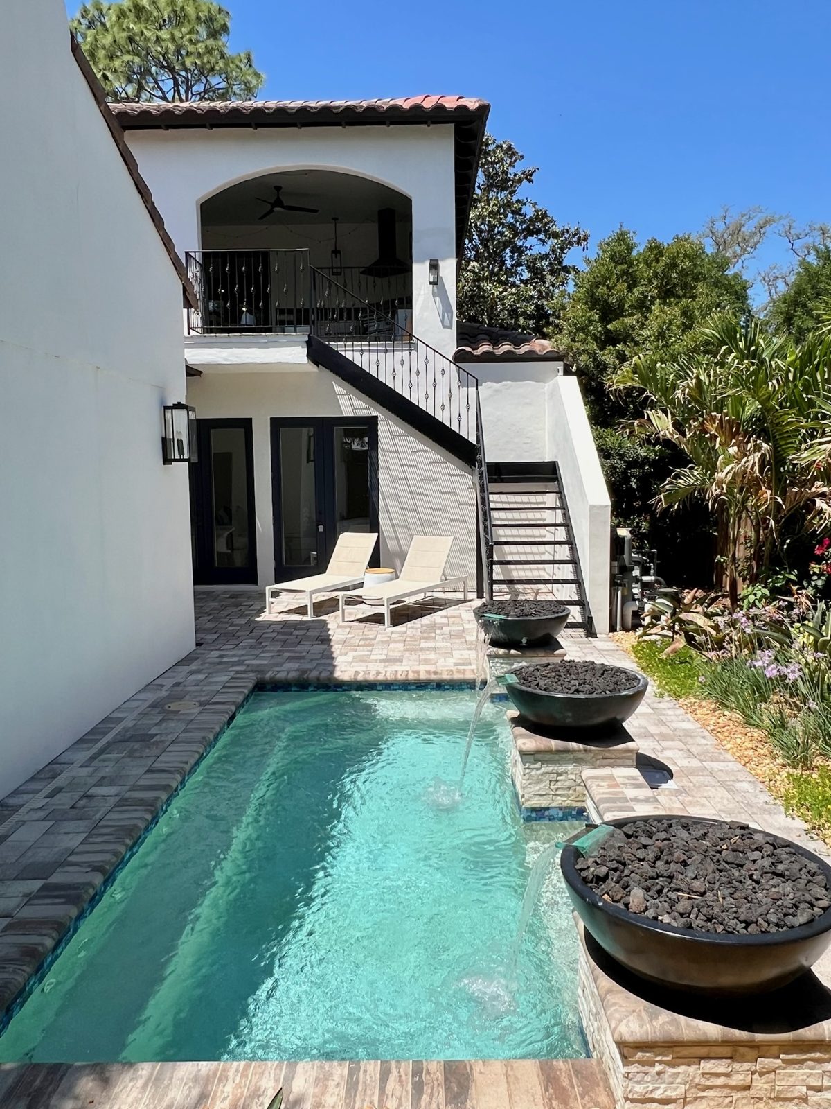 Backyard pool with fire bowls and a Mediterranean style exterior