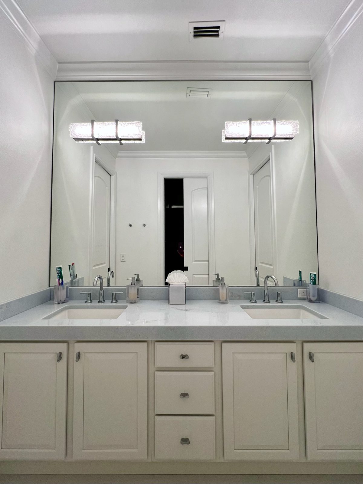 Double vanity with framed mirror wall and linear sconces