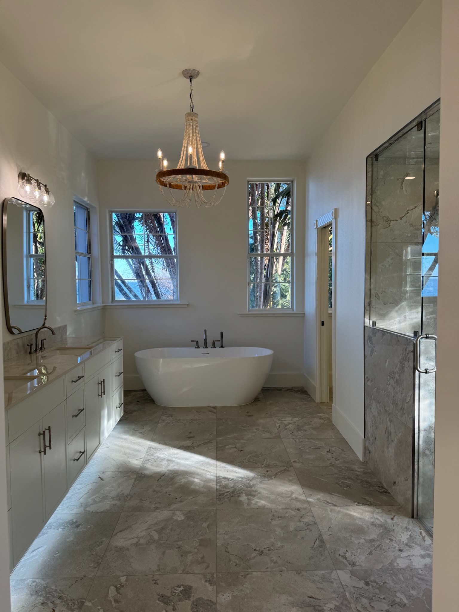 Freestanding soaking tub beneath a beaded chandelier