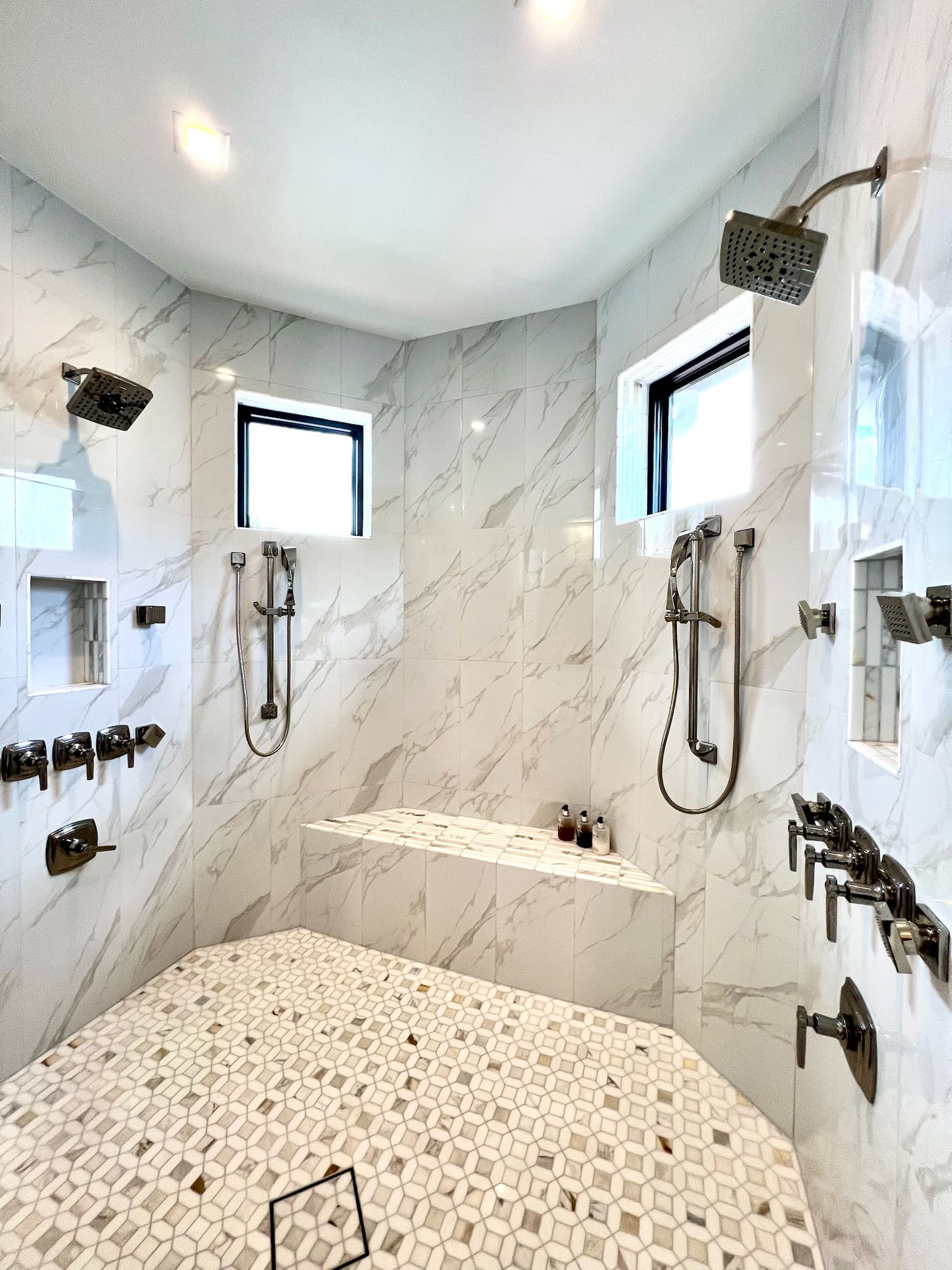 Marble shower with dual fixtures and mosaic floor