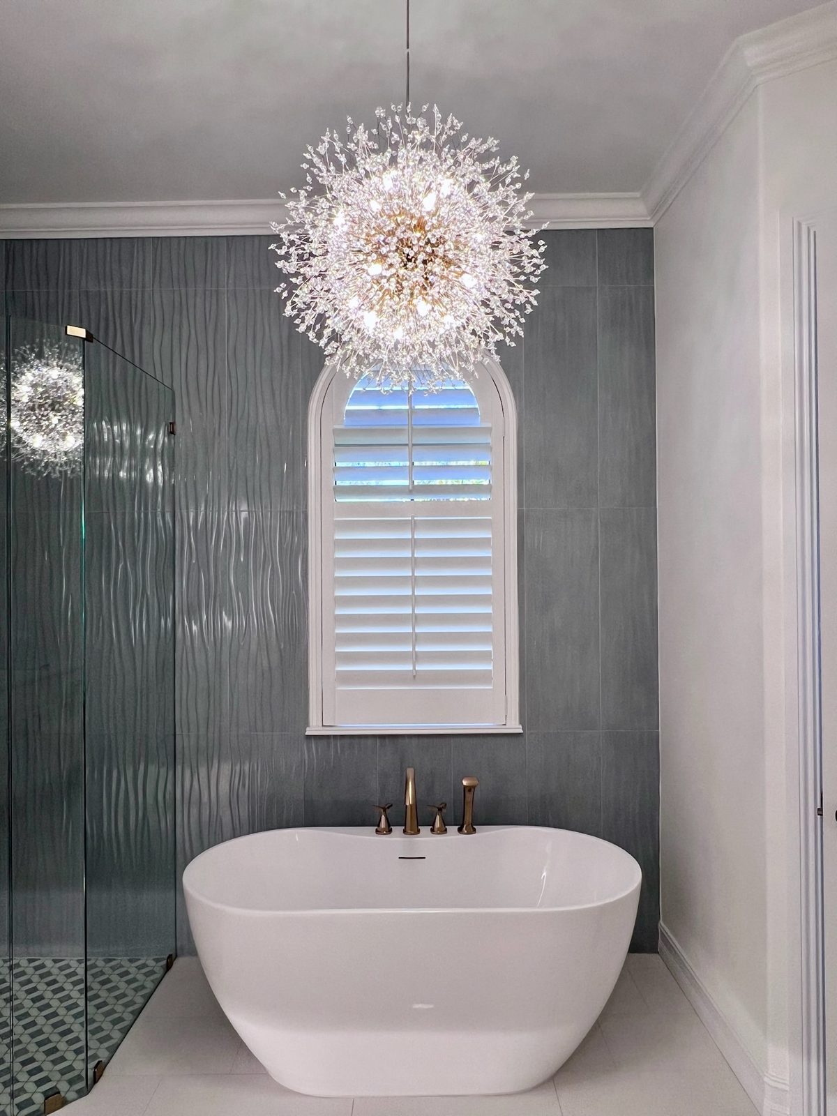 Primary bath with freestanding tub and starburst chandelier