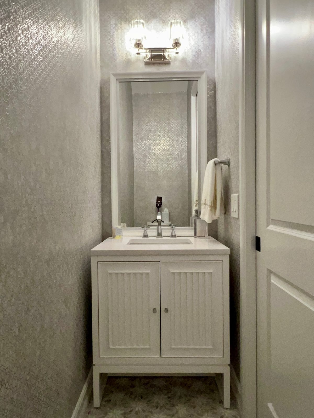 Powder room with textured wallcovering and beadboard vanity