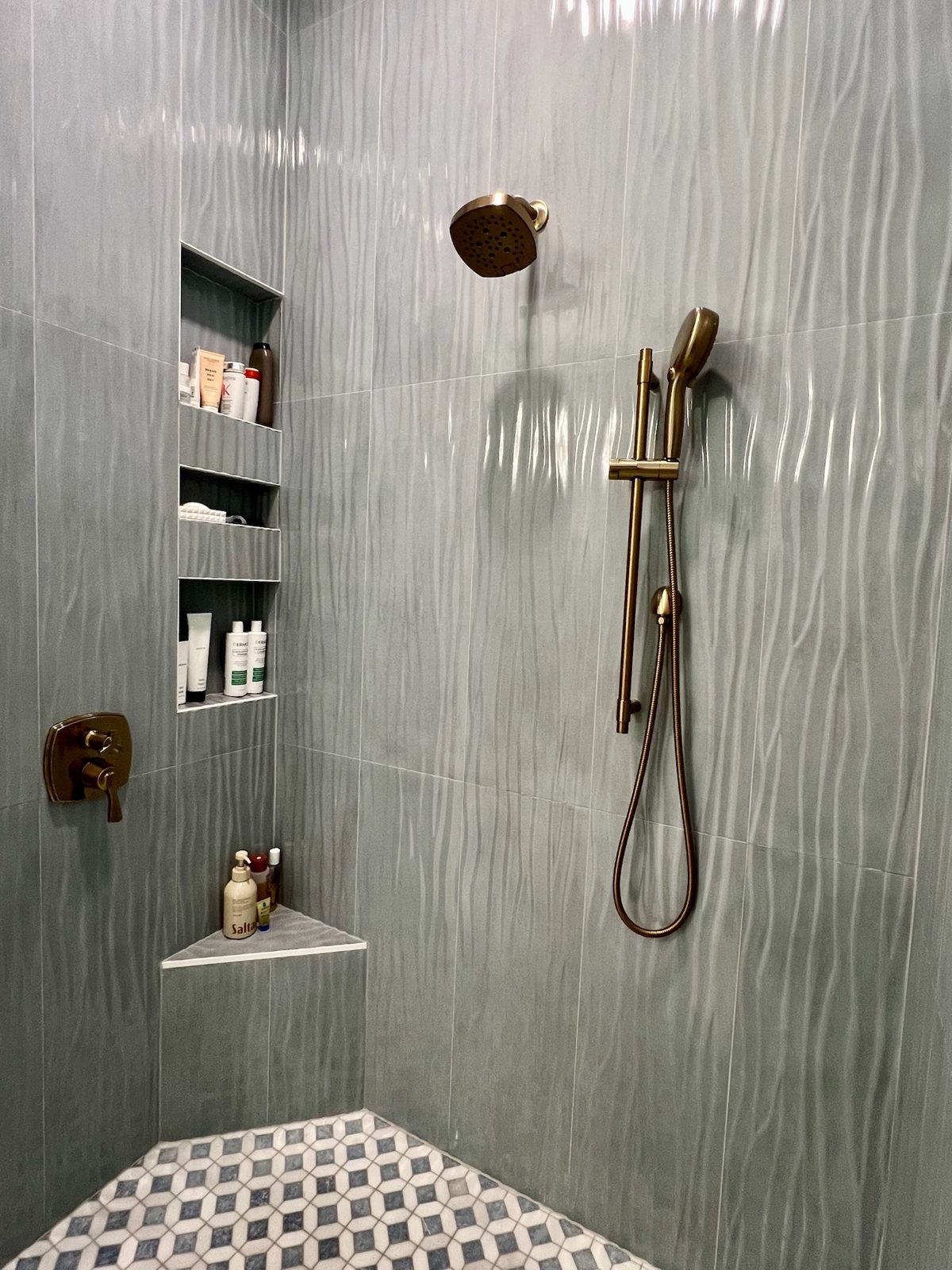 Walk-in shower with brass fixtures and tiled niches