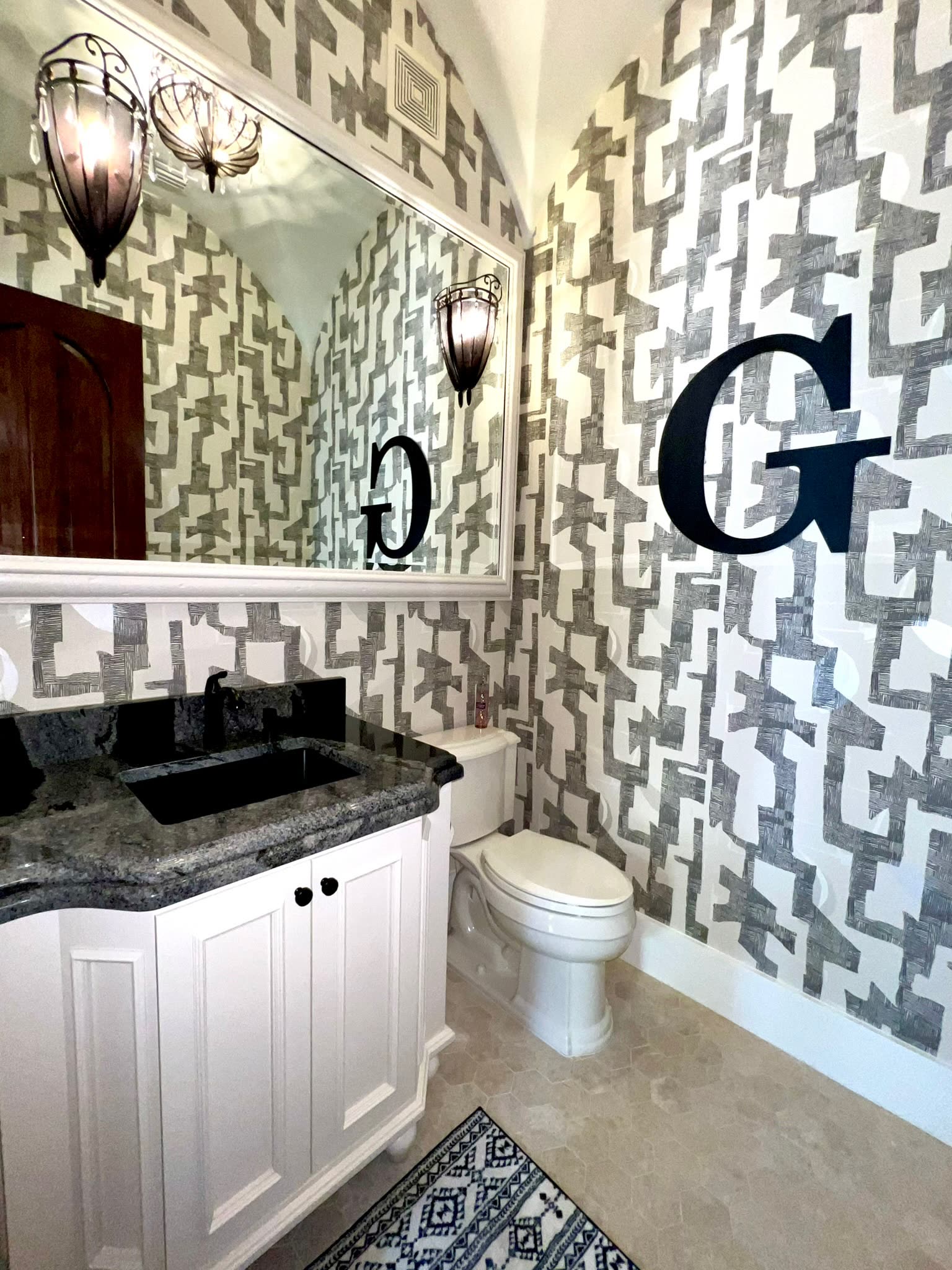 Powder room with graphic wallcovering and dark stone top