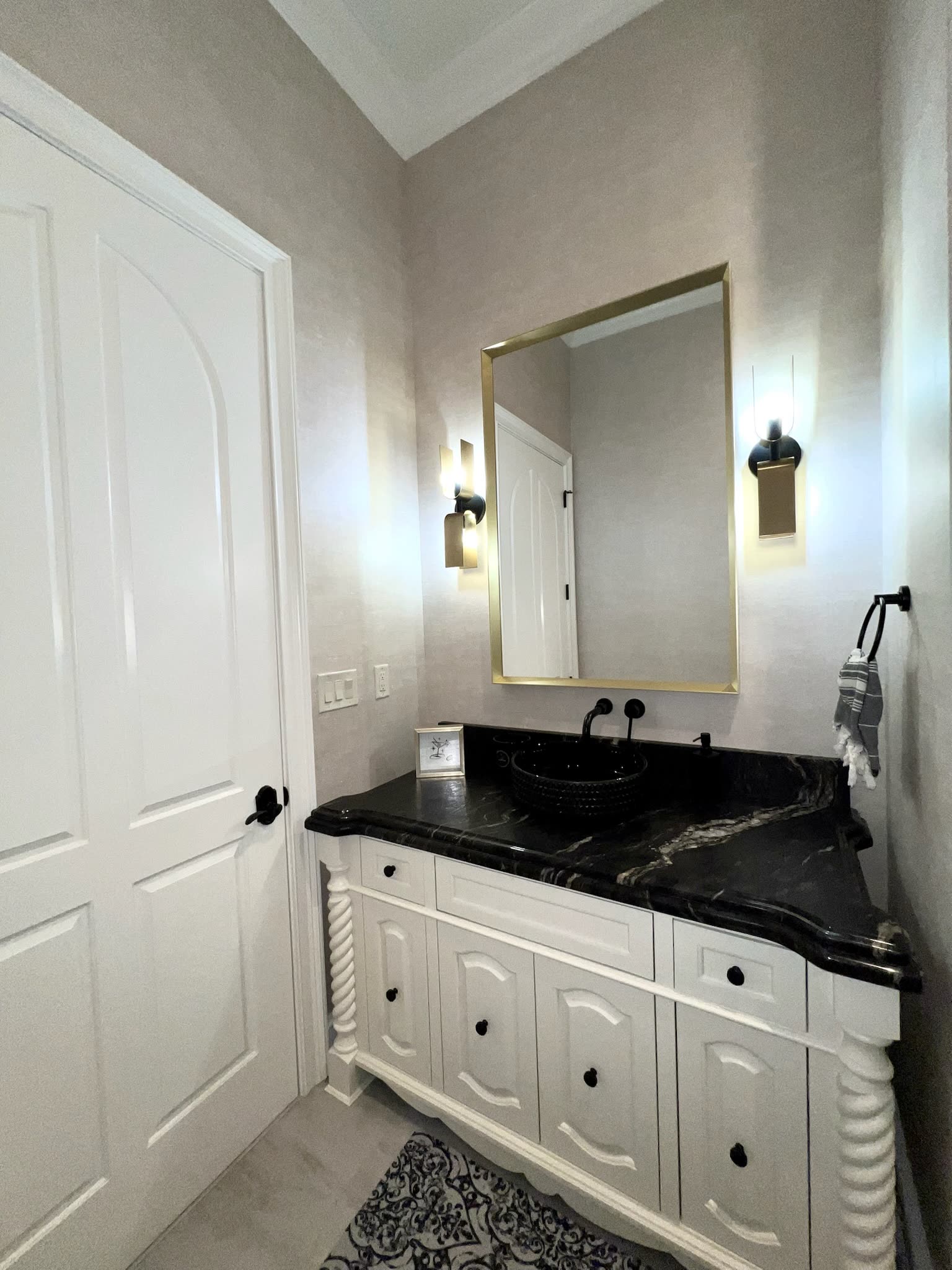 Guest bath with black granite top and brass sconces