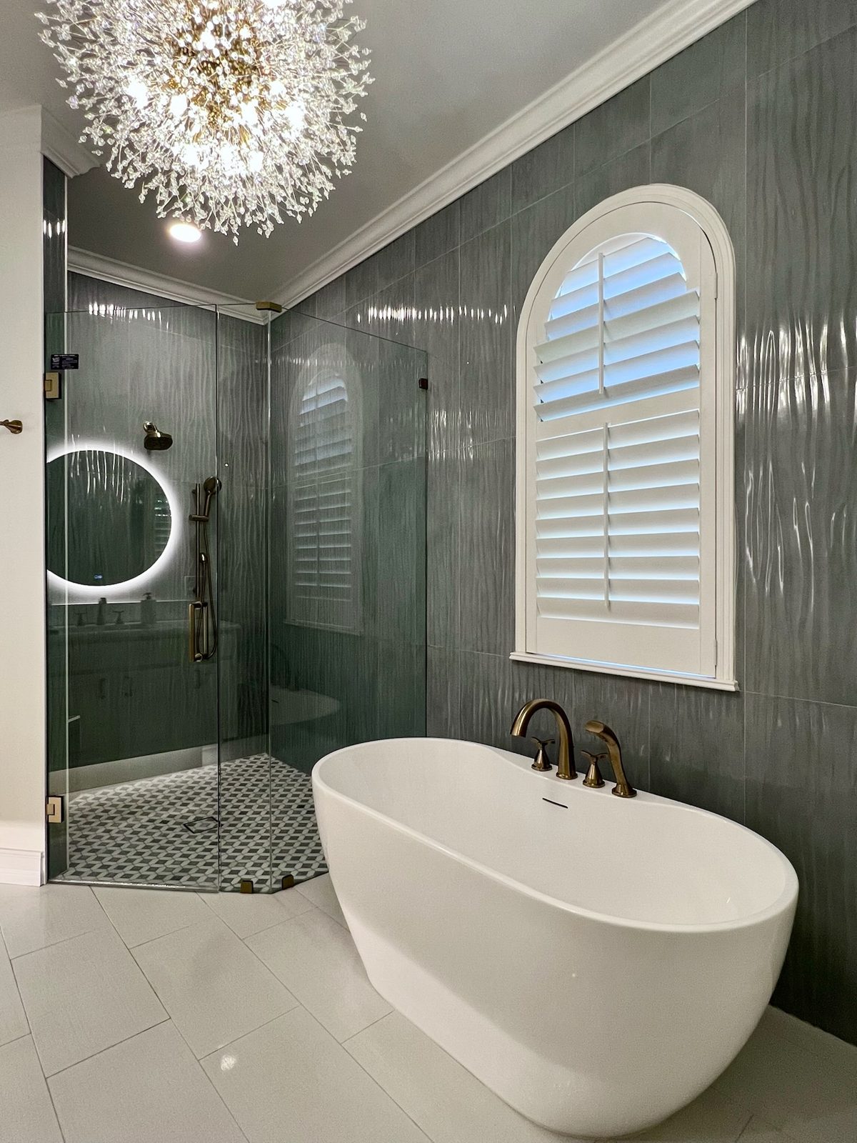 Primary bath with textured green tile and glass shower enclosure